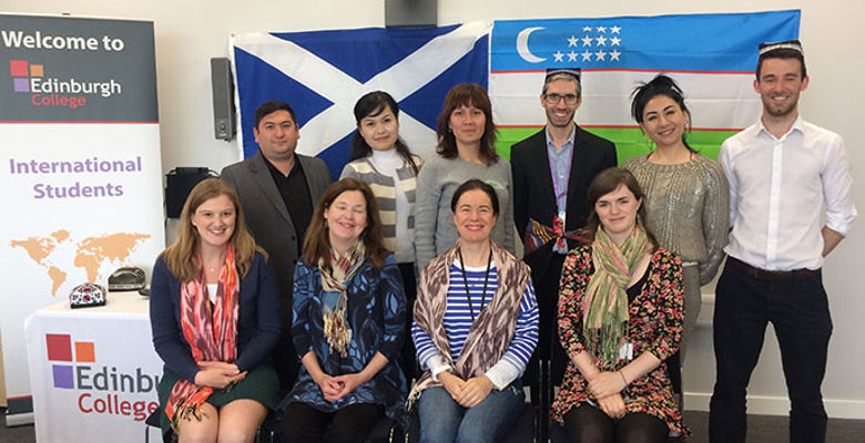 A group of diverse individuals poses in front of an "International Students" banner, with a Scottish flag in the background.