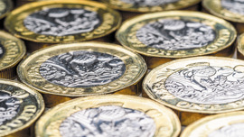 A selection of pound coins all lying flat.