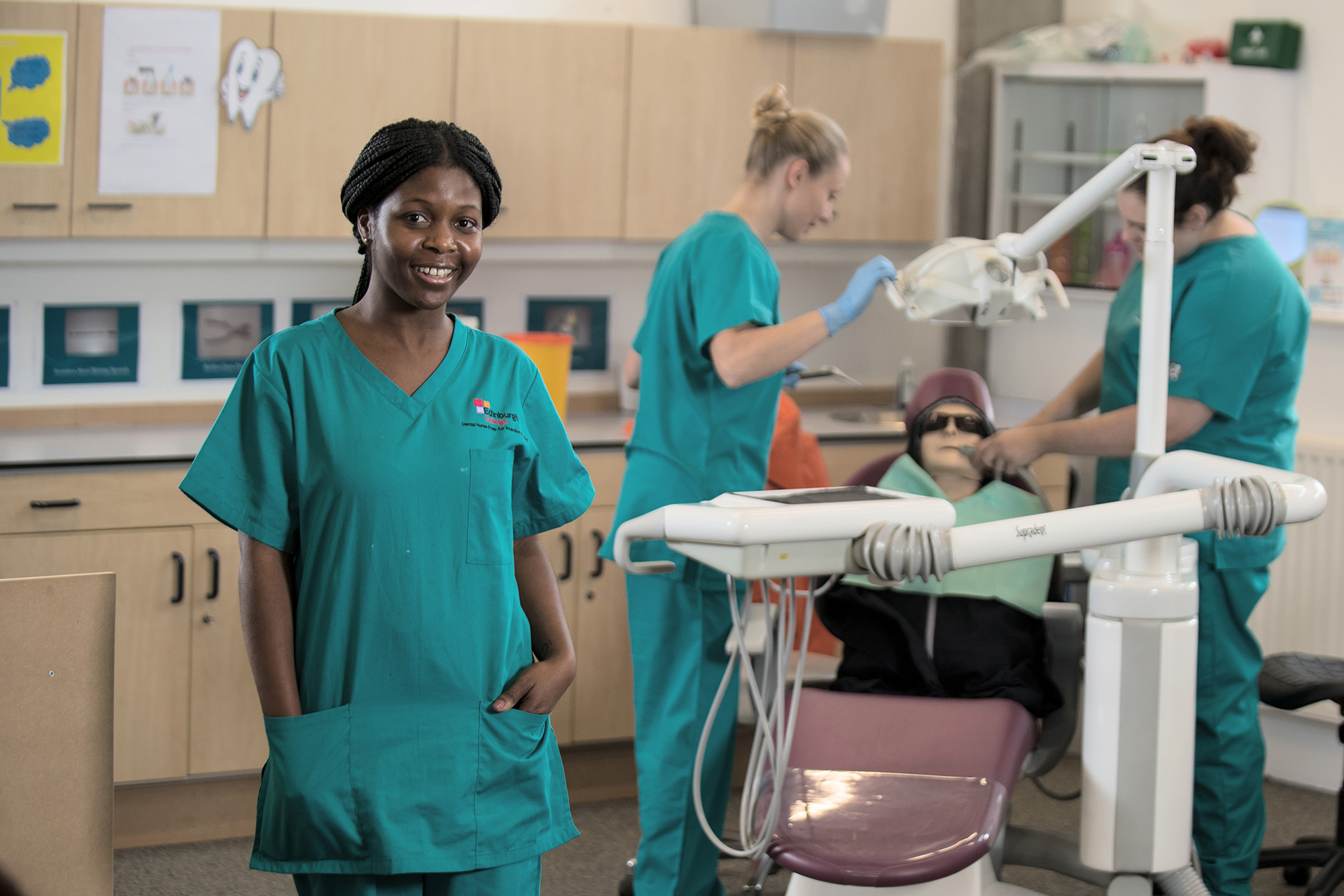 Health professions student wearing blue scrubs in a dental classroom.