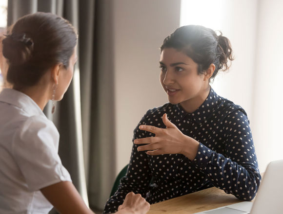 Person talking and making hand movements while the other person listens.