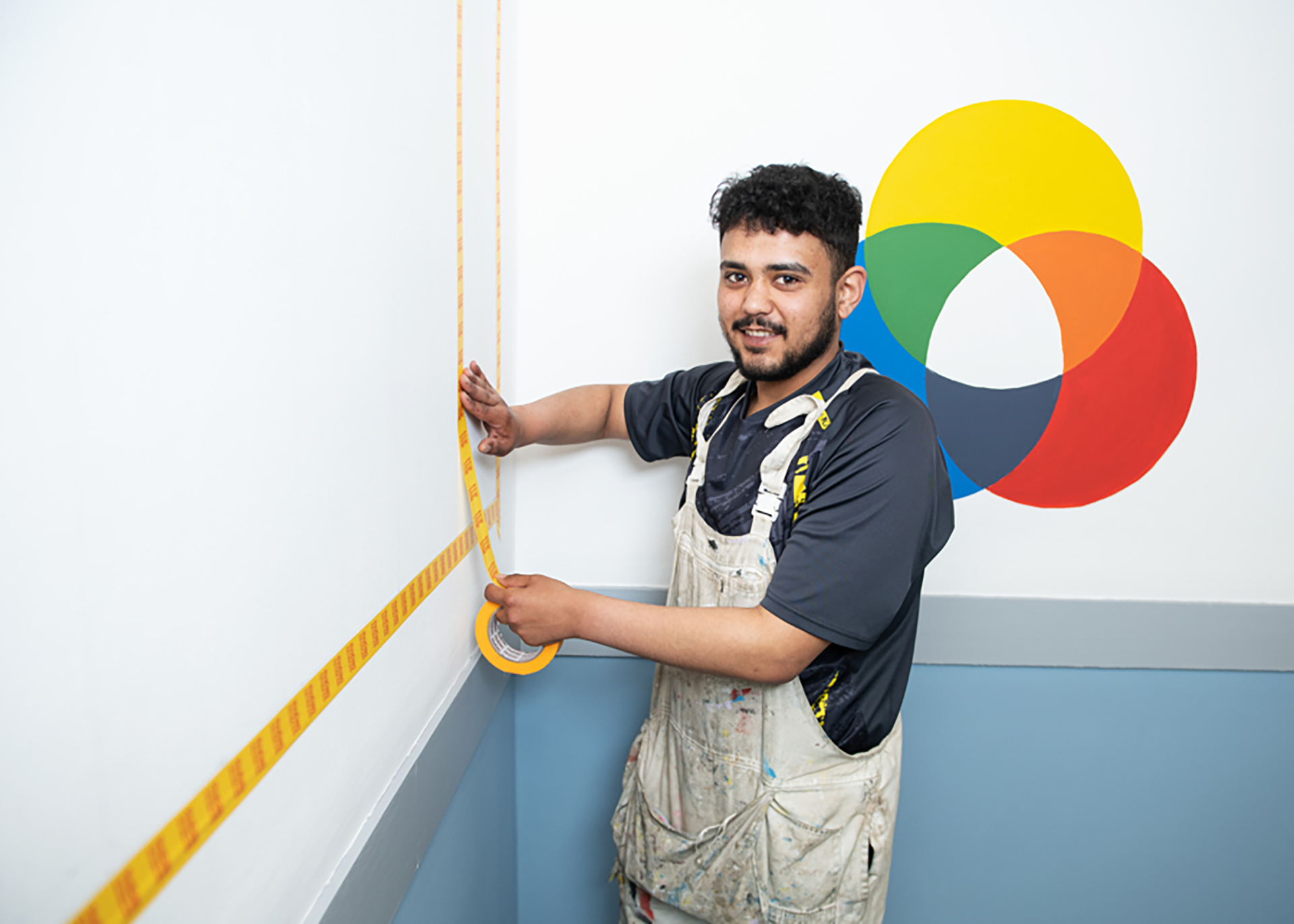Construction student taping a wall ready for it to be decorated.