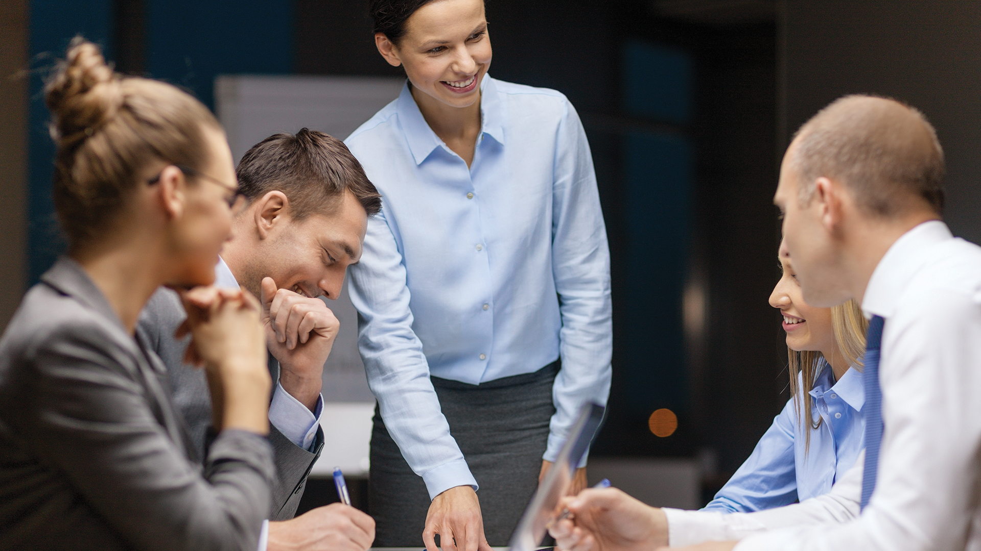 Group of employees wearing suits having a discussion at a meeting. 