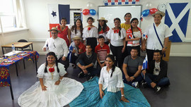 A group of individuals in colorful traditional clothing poses together in a room, showcasing cultural pride and community spirit.