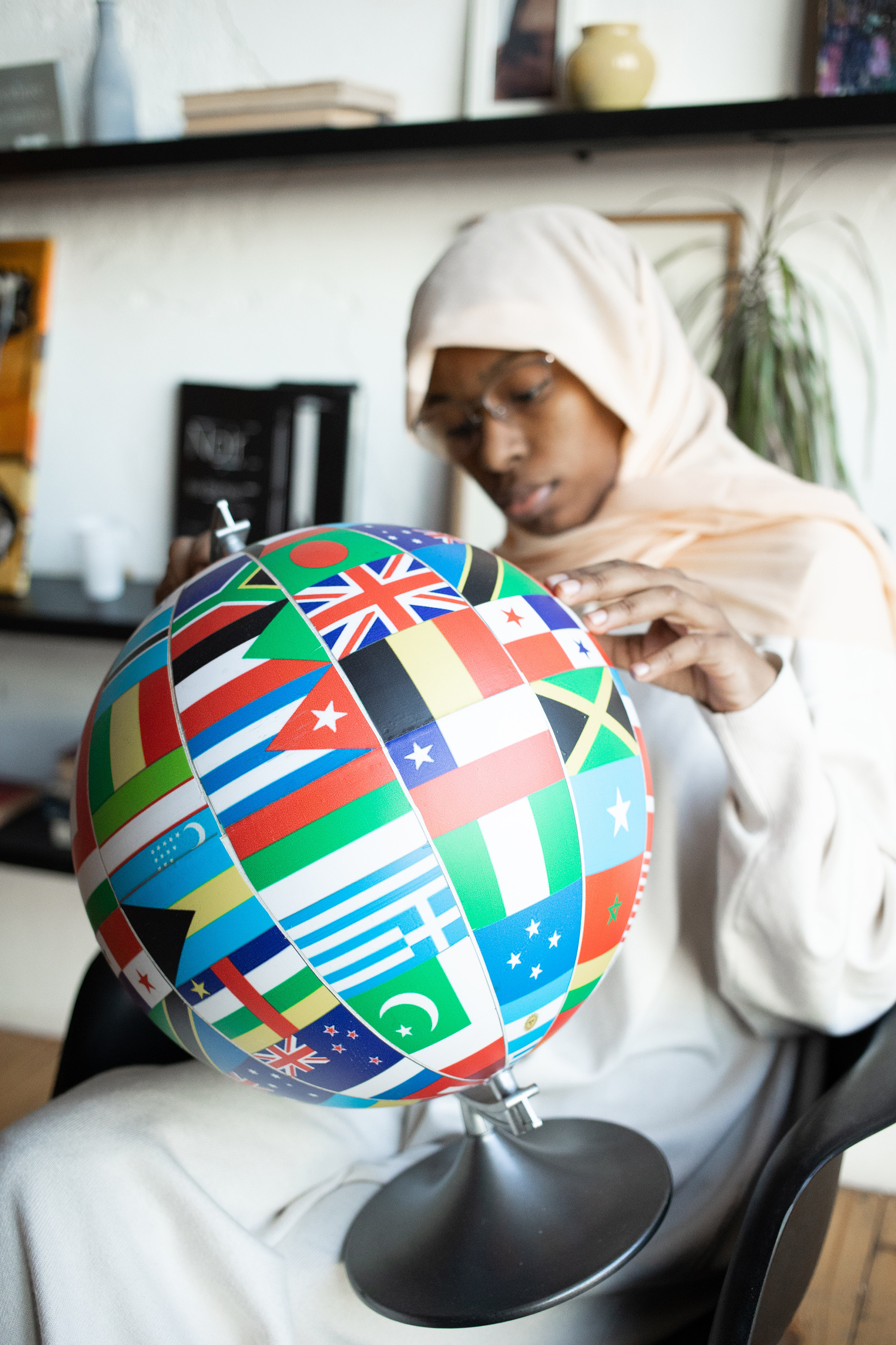 Person holding a globe with lots of different country's flags on it.