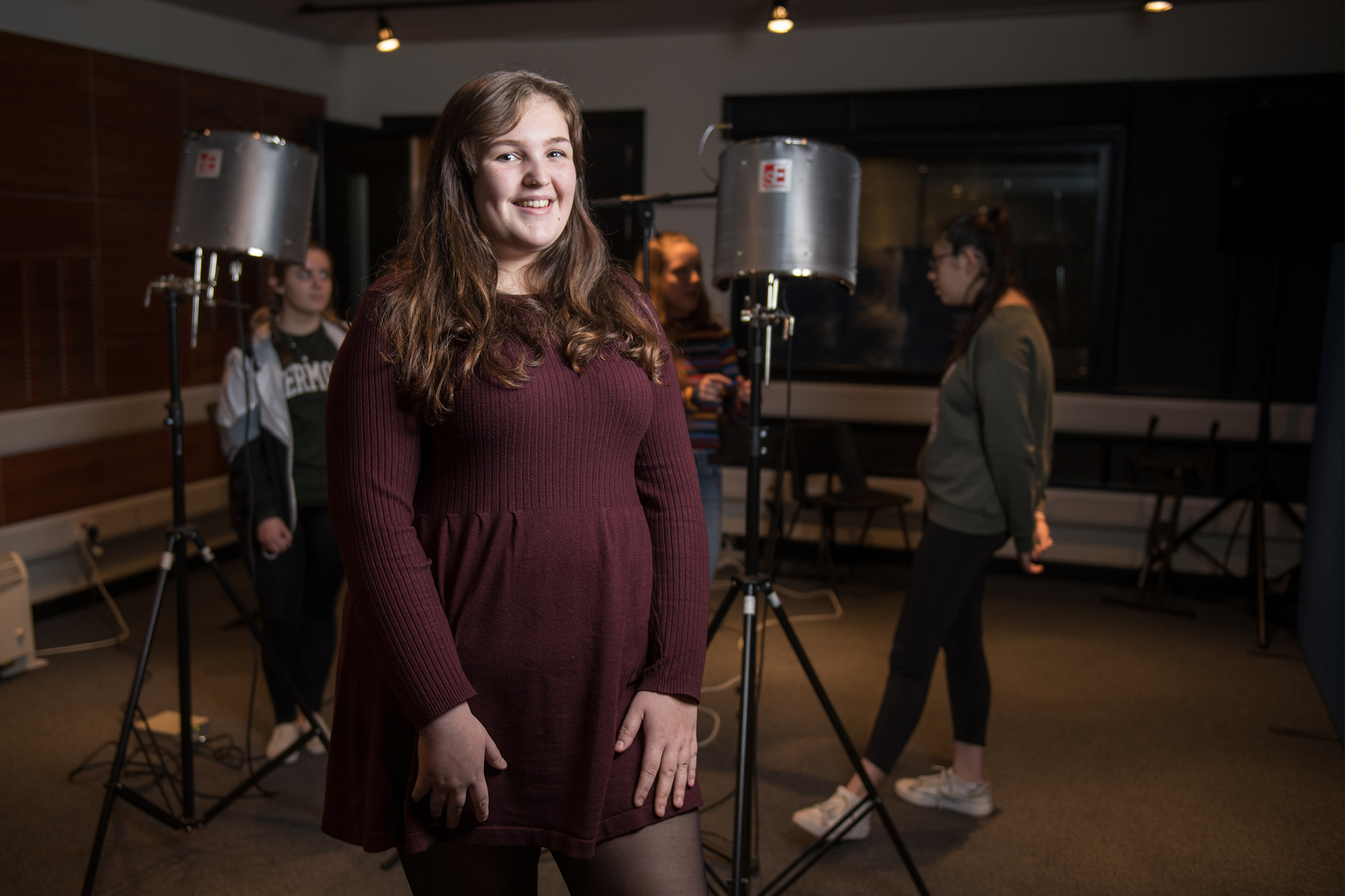 Music and Sound Production student standing in front of a microphone in a recording studio.