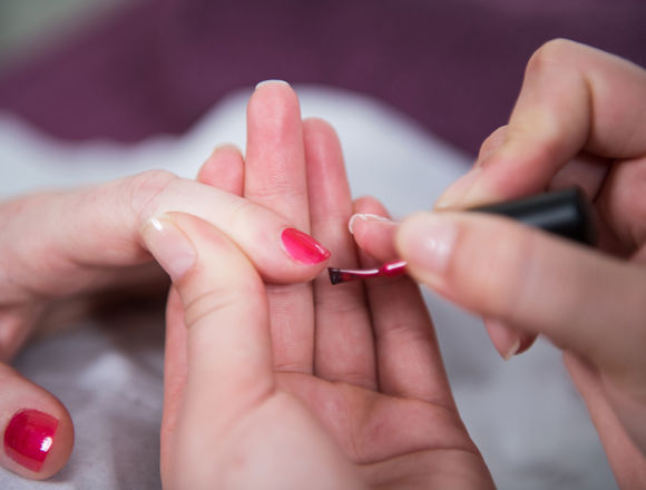 Close up of beauty student applying nail polish.