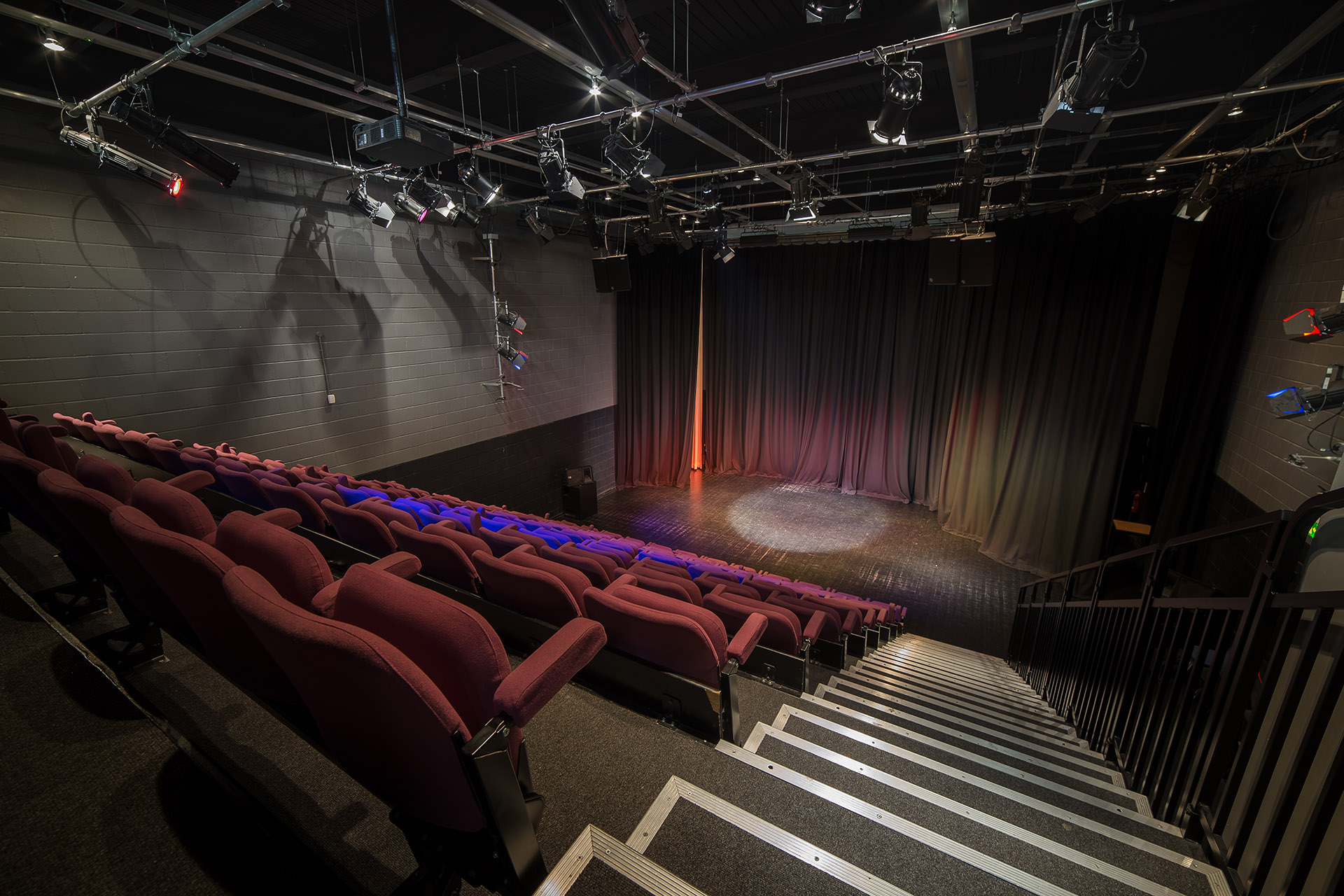 Back of the auditorium showing tiered seating, stage and lighting.
